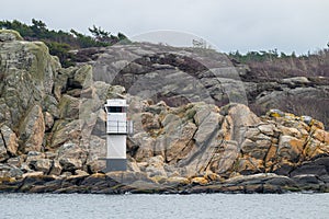 Small light house by steep cliffs..