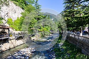 Kura river in Borjomi Cental Park in Georgia, with pedestrian promenade, bridges and lush green trees photo