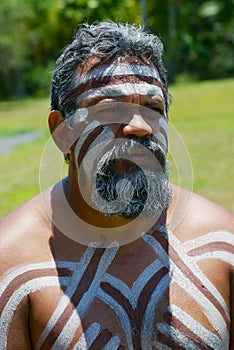 Portrait of aborigine actor with traditional face and body makeup in Tjapukai Culture Park in Kuranda, Queensland, Australia.