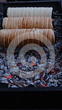 Kurtos kalacs (Chimney Cakes) baking on roll spinning over hot coals.