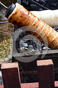 Kurtos kalacs or chimney cakes, preparing on charcoal grill, street food traditional Hungarian