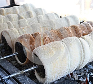 Kurtos kalacs or chimney cakes, preparing cooking on charcoal grill