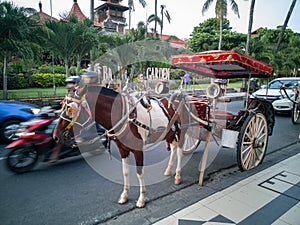 Kuta, Bali in Indonesia - December 2018: Horse and carriage waiting for customers in the city street. Traffic in the