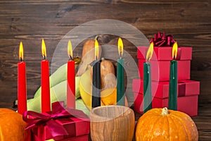 Kwanzaa festive concept with burning candles, gift box, pumpkins, ears of wheat, grapes, corns, banana, bowl and fruits on wooden