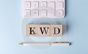 KWD on wooden cubes with pen and calculator, financial concept