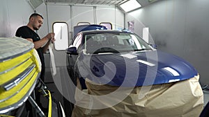 Kyiv, Ukraine - August 12, 2023: Paint shop at the car service station. The master of the paint shop prepares the car for painting