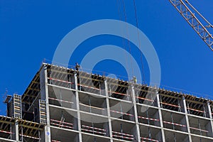 Professional high-rise installers buildings work on the top floor of a building under construction.