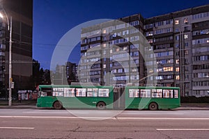 Green trolleybus on the street of Kyiv in the residential area of Troyeschina at night. Trolleybus 