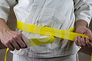 Kyokushinkai karate athlete ties yellow belt around his waist photo
