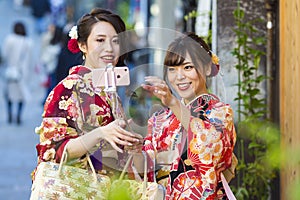 KYOTO, JAPAN - NOVEMBER, 8, 2019: Couple of  Young Japanese Girls Wearing Traditional Geisha`s Kimono Taking Photos On Kyoto