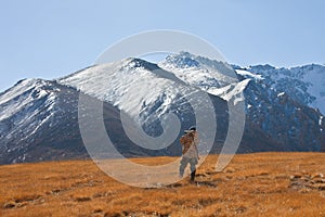 Kyrgyz hunter in the mountains looking through binoculars.