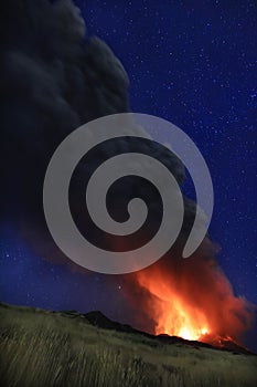 L\'Etna in Sicilia grande eruzione con grandi emissioni di cenere dal cratere del vulcano nel ciel notturno stellato