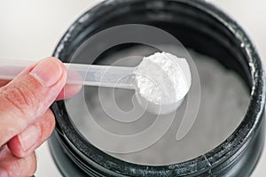 L-Glutamine supplement. Man holding scoop with L-Glutamine powder inside