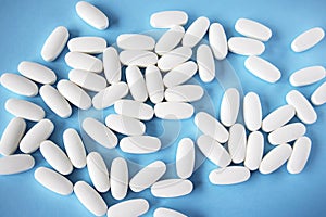 L glutamine white oval tablets scattered on a blue background, view from above