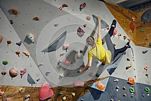 L:ittle girl, child attending bouldering course, training, climbing wall indoors. Sport education