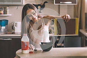 L woman breakfast pours cereal from box into bowl