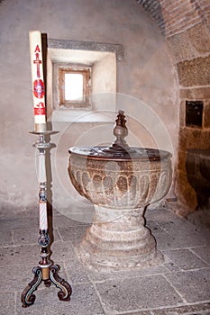 Baptismal font and baptism candle, Our Lady of the Assumption, La Alberca, Salamanca, Spain photo