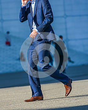La defense, France- April 09, 2014: side view of businessman walking in a street. He wears a very elegant blue suit and high