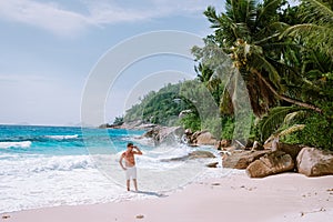 La Digue Seychelles, young men on vacation at the tropical Island La Digue, mid age guy walking on the beach during