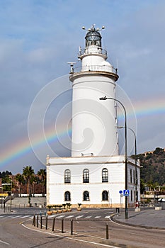 La Farola lighthouse in Malaga, an old coastal building in the harbour, with a rainbow in the background, Spain photo