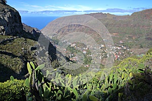 LA GOMERA, SPAIN: General view of Valle Gran Rey from a hiking trail near El Cercado and with cactus plants in the foreground photo