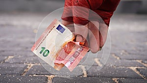 La mano de Tramp con un guante rojo levanta un billete de diez euros photo