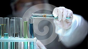 Lab assistant adding liquid from test tube with cross symbol, illegal research