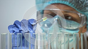 Lab assistant examining green organic pill, pharmaceuticals and homeopathy