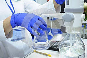 Lab assistant hands working with titrator to measure quality of drinking water