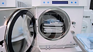 The lab assistant quickly fills in the white autoclave with package dental tools