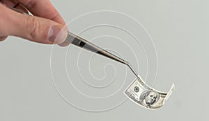 Lab, forensic scientist or medical professional with tweezers takes out rolled-up money. Hands in white gloves hold a