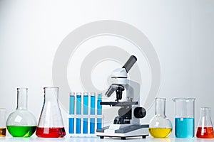 Lab microscope with laboratory glassware on desk