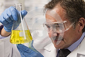 Lab scientist examining beaker, horizontal