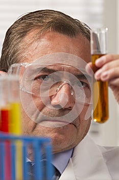 Lab scientist examining test tube, vertical