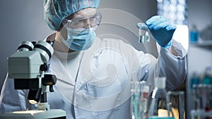 Lab technician examining sample of fluid for presence of unnecessary sediments photo
