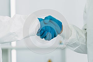 Lab Technician in Personal protective equipment  PPE suit Vaccines shake hand together