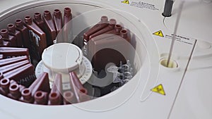 A lab worker doing a blood test. loads the tubes into the machine. The assistant loading the vial into the laboratory
