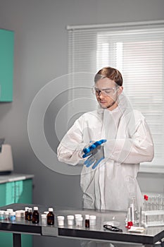 Lab worker putting on blue sterilized medical gloves to do some tests