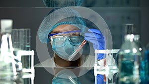 Lab worker studying meat sample in test tube, genetically modified organism