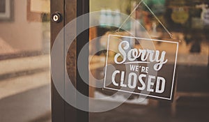 Label `Sorry we`re closed` notice sign wood board hanging on door front coffee shop.