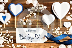 Label With White Decoration, Heart, Flower, Text Welcome Baby