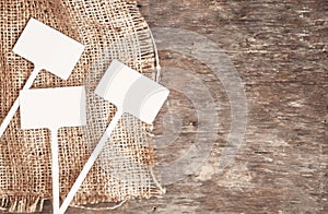 Labels-markers for plants lie on burlap, on a wooden brown background., Top view