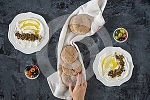 Labneh labaneh middle eastern soft white goat`s milk cheese with olive oil ,olives , za`atar , lemon, with woman hand holding o photo
