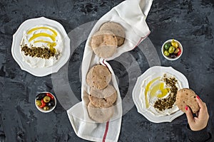 labneh labaneh middle eastern soft white goat`s milk cheese with olive oil ,olives , za`atar , lemon, with woman hand holding o