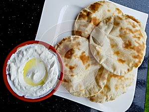Labneh and pitta flat bread, viewed from above. Lebanese yoghurt cream cheese dip, served with olive oil
