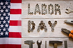 Labor day. American flag and Inscription labor day and various tools on a light wooden background