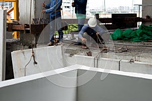 Labor man working on construction site with helmet pulling concrete slabs using pulley