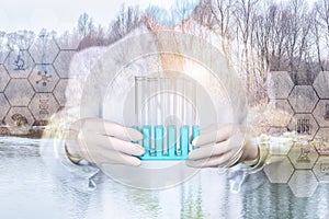 A laboratorian in mask and gloves is holding a set of test tubes with nature water samples