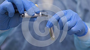 The Laboratory Assistant is decanting a green liquid into a Test Tube with a yellow Liquid.