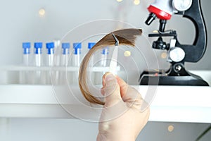 Laboratory assistant examines a hair sample, curls in a package for research by genetic research in laboratory, trichologist